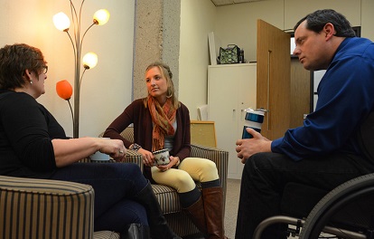 a male and two females having a discussion in a room